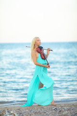 Girl on the beach plays the violin.