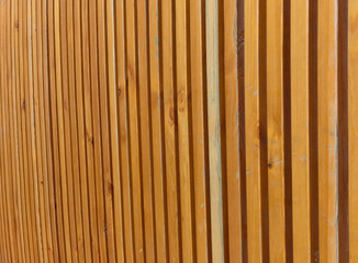 Perspective. Background of striped yellowish brown vertical wooden poles or boards with  gaps, slits.