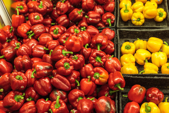 Red and yellow peppers displayed in trays at a grocery store