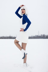 girl in a white wig posing in winter in a field in a blue turtleneck