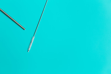 Reusable eco friendly metal straw and cleaning brush isolated on blue background with copy space