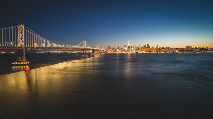Obraz premium Panoramic beautiful scenic view of the Oakland Bay Bridge and the San Francisco city in the evening, California