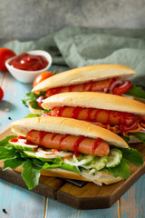 Traditional american fast food. Barbecue grilled Hot dog with fresh vegetables on wooden table with copy space.