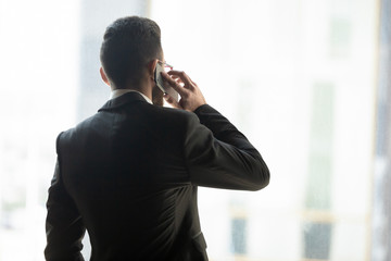 Rear view confident businessman talking on phone with business partner