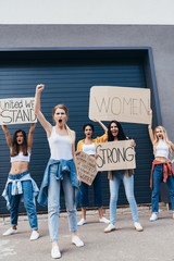 full length view of screaming multiethnic feminists holding placards with slogans on street