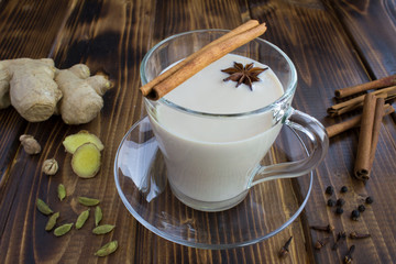 Tea masala in the glass cup and ingredients on the brown  wooden background. Closeup.