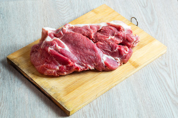 Raw meat on wooden board on table