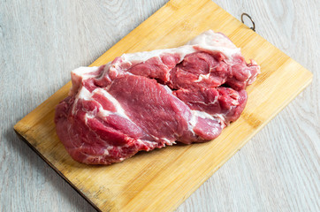 Raw meat on wooden board on table