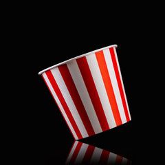 Empty popcorn striped bucket isolated on black background