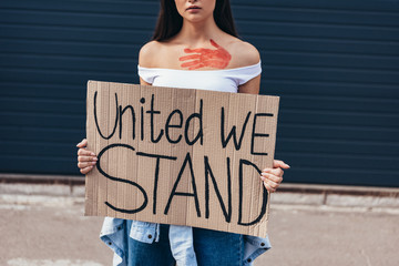 cropped view of feminist holding placard with inscription united we stand on street