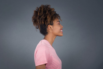 Profile of smiling African American woman with healthy pure skin, has bushy hairstyle, has contemplative expression, ready to have outdoor walk, isolated over white studio wall with copy space