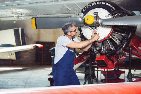 Aircraft mechanic repairs an aircraft engine in an airport hangar