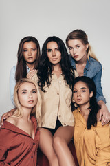 Obraz premium front view of five attractive multiethnic feminists in colorful shirts looking at camera isolated on grey