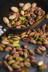 Bowl with pistachios on a black table.