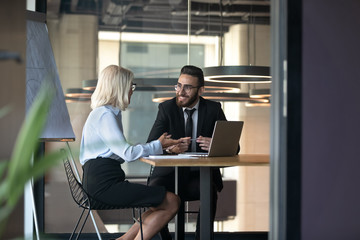 Mature businesswoman and young employee discussing strategy in boardroom
