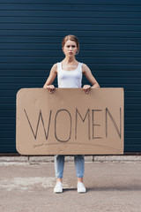 full length view of feminist holding placard with word women on street
