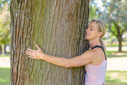 Young woman daydreaming while hugging a tree