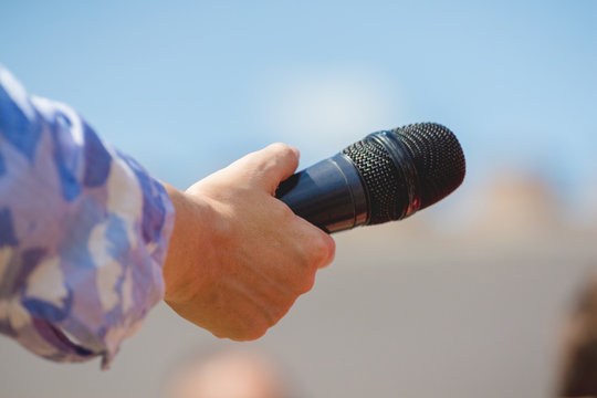 The journalist holds a microphone in his hand during an interview_