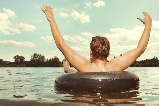 Funny Man In Sunglasses Swimming In Lake On Inner Tube