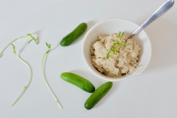 Tasty hummus in the white plate with green cucumbers