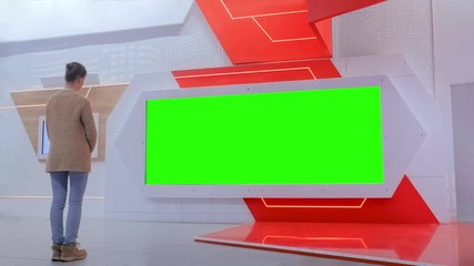 Green screen, mock up, template, copyspace, chroma key concept. Woman looking at blank large interactive wall green display at modern technology exhibition or museum with futuristic sci-fi interior