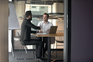 Businessmen partners handshaking at meeting in boardroom