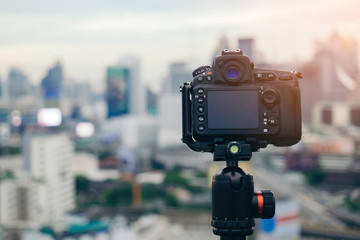 Digital camera on tripod with city view on background