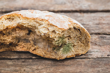 Mildew on a slice of bread, lying on a wooden surface. Stale bread, covered with mildew_