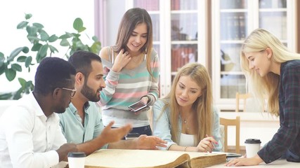 Group of multiracial people studying with books in college library.