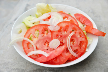  Close up shot of a white bowl with lettuce and tomatoes