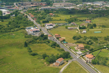 Aerial view from the aircraft window of Bilbao surrounding area. Photography of houses roofs and the highway in Basque country in summer day. Photo is suitable for greeting card, postcard, poster.