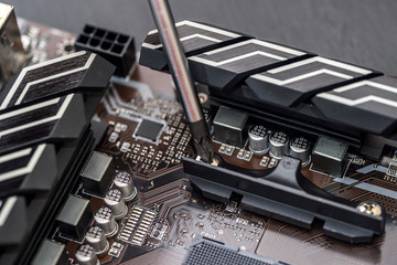 Screwdriver screw bolt on motherboard. Close up