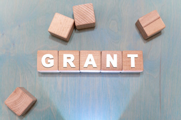 Grants financial fund support concept. Grant word arranging with wood cubes.