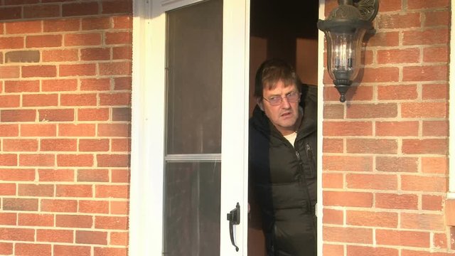 Old man peeks head out of the house door.