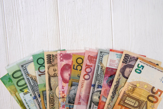 Colorful international banknotes in fan on light wooden table