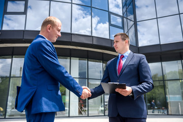 Businessmen making deal and handshaking outside building