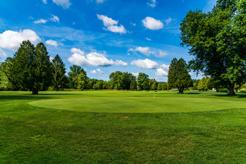 Fototapeta na wymiar golfcourse with trees and blue clouds 