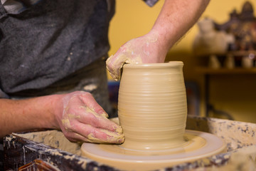 Professional male potter working with clay on potter's wheel