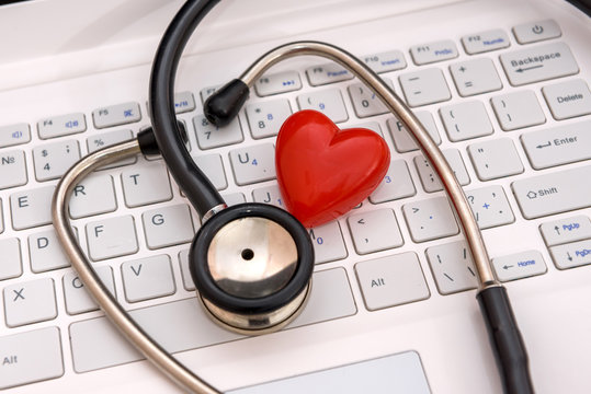 Stethoscope with red heart on laptop keyboard