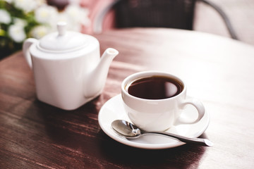 Teapot and cup of tea on wooden table.