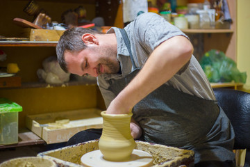 Professional male potter making jug in pottery workshop