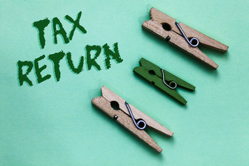 Text sign showing Tax Return. Conceptual photo which taxpayer makes annual statement of income circumstances Three brown green vintage clothespins clear background Holding things