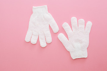 Woman exfoliating massage glove for shower on pink background.Gloves for use in the shower for massage and scrub. Beauty background with cosmetic products. Beauty, health and spa concept