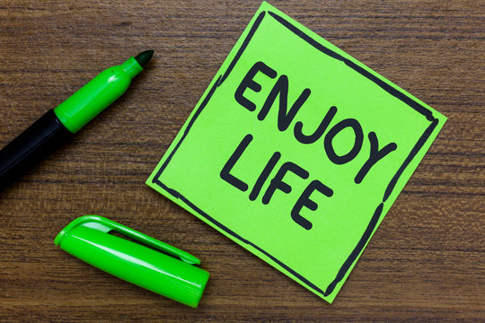 Conceptual hand writing showing Enjoy Life. Business photo showcasing Any thing, place,food or person, that makes you relax and happy Green Paper Communicate ideas Marker Wooden background