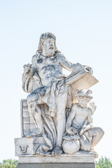 Obraz premium Sculpture of scientist with a book and his scholar on Zoll Bridge in Magdeburg downtown at direct light background, Germany, details, closeup