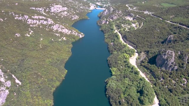 Aerial view of Aliakmonas river in valley and country road on the side, Veria Greece,  motion in front of a drone