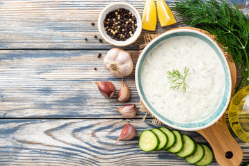 Traditional greek yogurt sauce tzatziki in bowl on wooden table. Top view. Copy space.