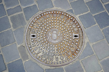 Cast iron ornamented manhole cover in Budapest, Hungary. Closeup of duct  manhole cover with Budapest Coat of Arms at the Old Town district. Sewerage hatchway. Selective focus. Copy space