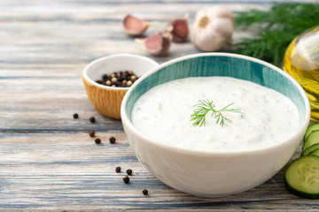 Traditional greek yogurt sauce tzatziki in bowl on wooden table. Selective focus.