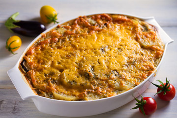 Traditional moussaka in baking dish on white wooden table